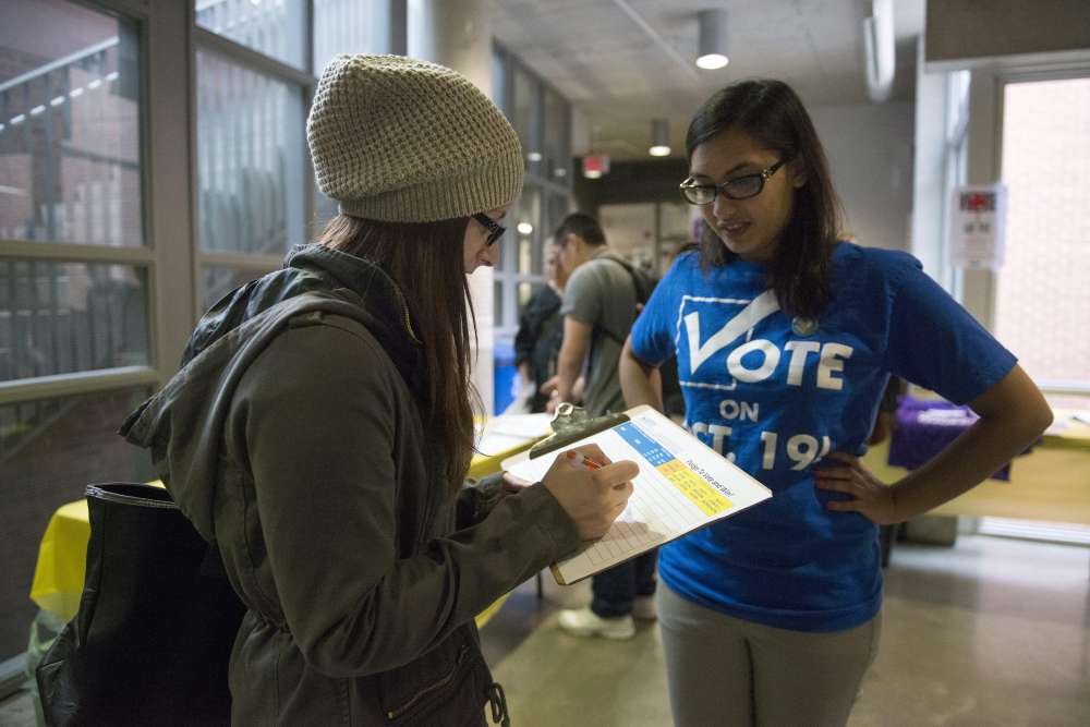 Rabbia Ashraf, vice-president internal at the Continuing Education Students' Association of Ryerson (CESAR) talks to 2nd year student Katey Agnitsch about voting. Elections Canada set up advance polling stations on the second floor of the Ryerson Student Centre at Ryerson University in Toronto, Wednesday, Oct, 7, 2015. THE CANADIAN PRESS/Marta Iwanek